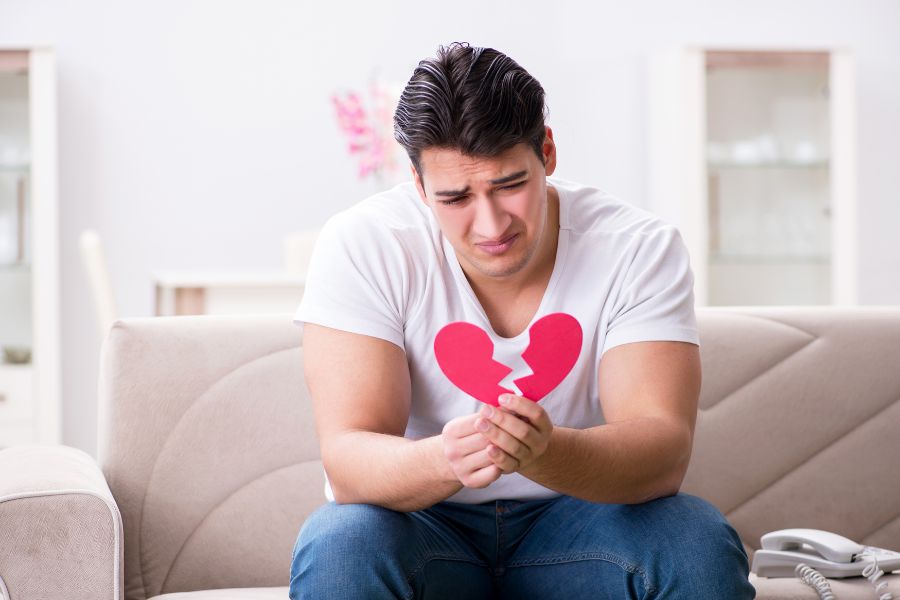 Blessure d'abandon: un homme triste tenant un coeur brisé à la main
